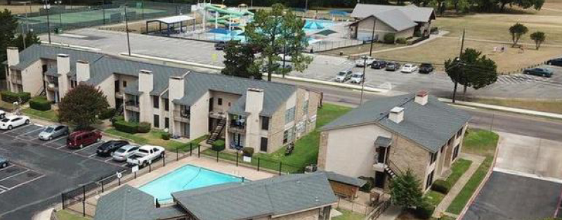 Aerial view of Parkview Apartments featuring a pool, with the sprawling Fairview Park, including the Splash Family Aquatic Center and tennis courts, in the background.