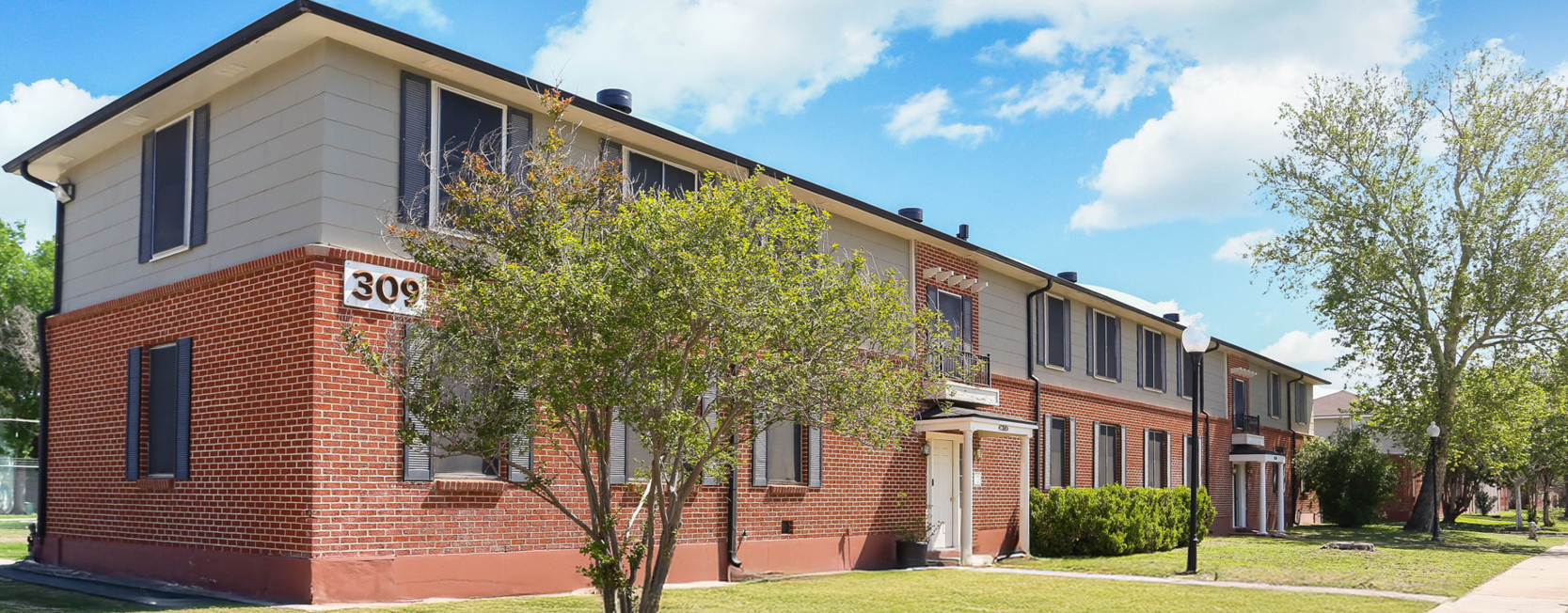 Port Townhomes in San Antonio, TX, showing a two-story red brick townhome with beige siding.